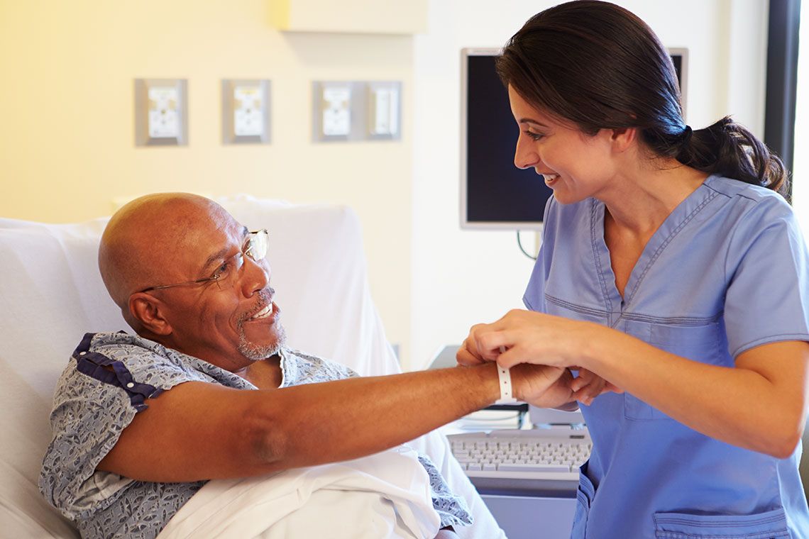 A medical practitioner putting a wristband on a hospital patient